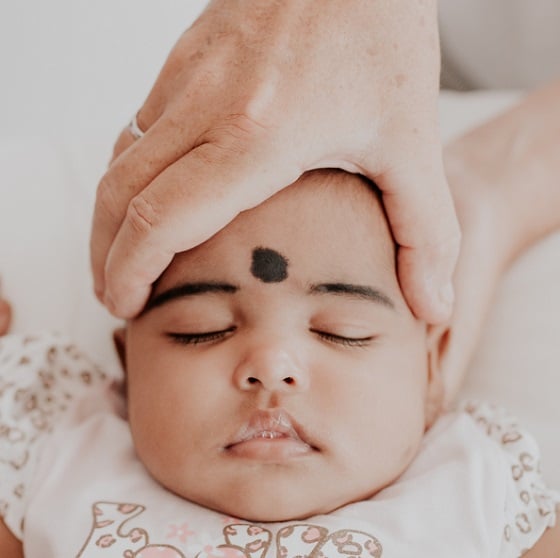 An osteopath gently cradles the head of a sleeping baby