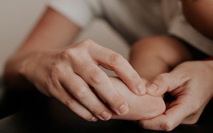 An osteopath's hands gently treat a child's hand and fingers