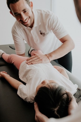 An osteopath is treating a little girl for w-sitting position.